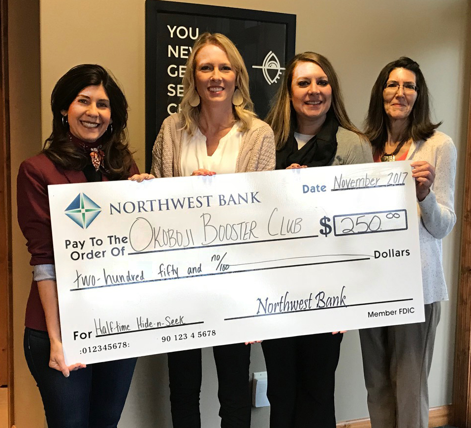 Image of Northwest Bank staff giving a donation check to Okoboji Booster club member Jill Harms