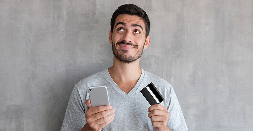 image of man holding credit card and phone